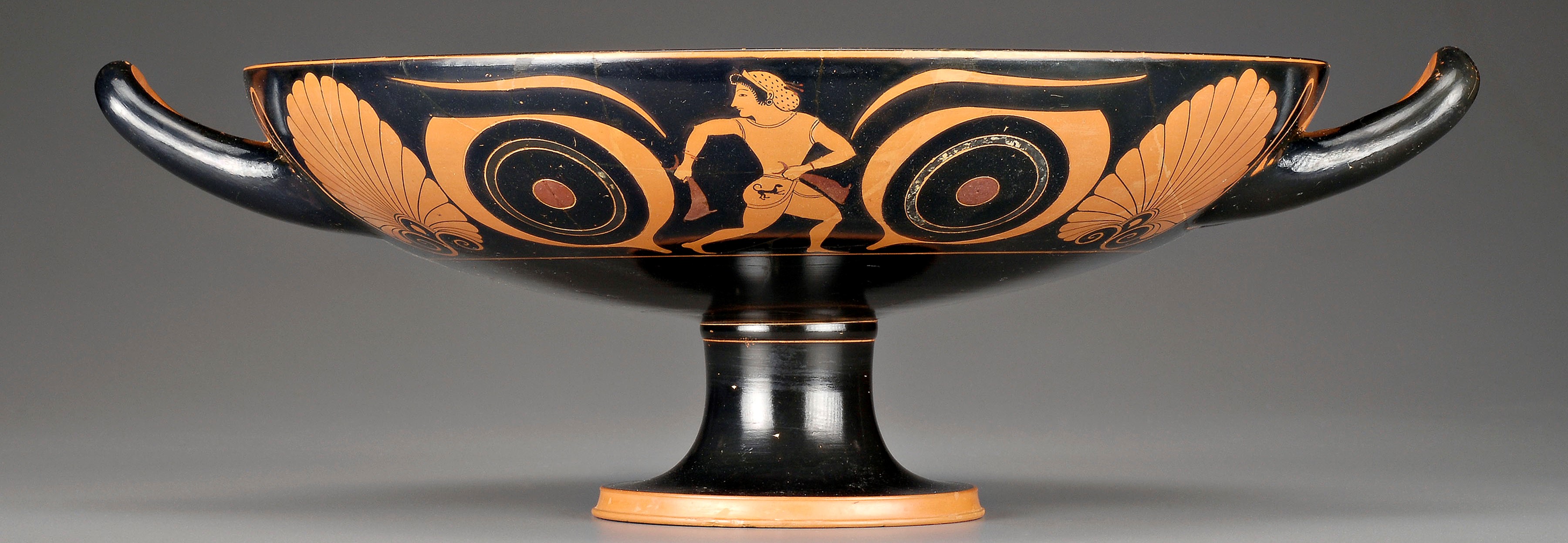 Ancient Greek pot painted with a man centered between two large eyes. 