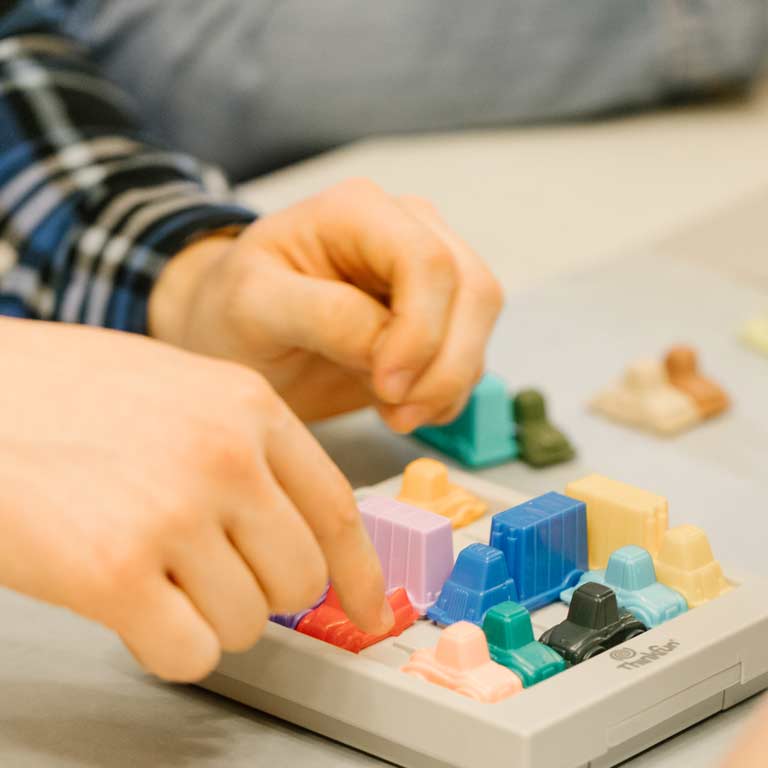 Close up of hands working on a 3-D puzzle. 